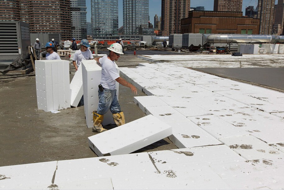Construction workers installing lightweight insulating concrete panels on a rooftop