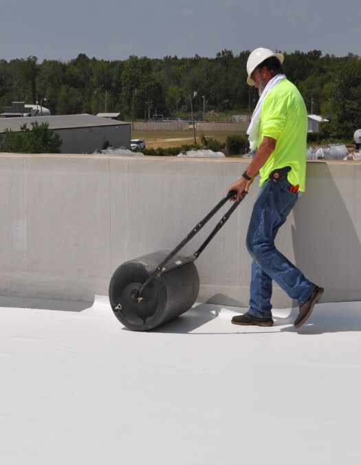 Contractor rolling our TPO roofing membrane