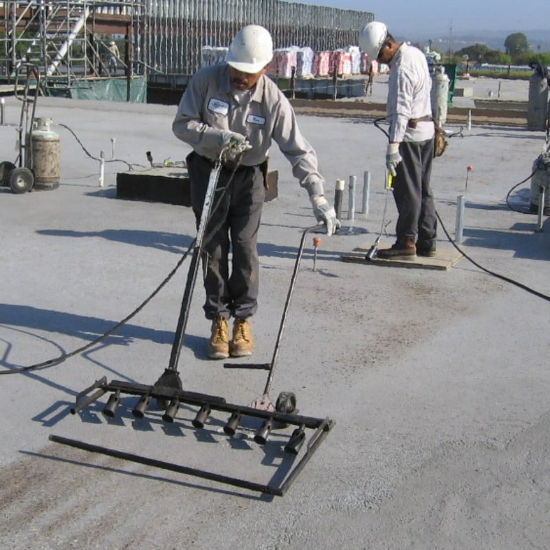 Roofers using lightweight insulating concrete materials on a flat roof