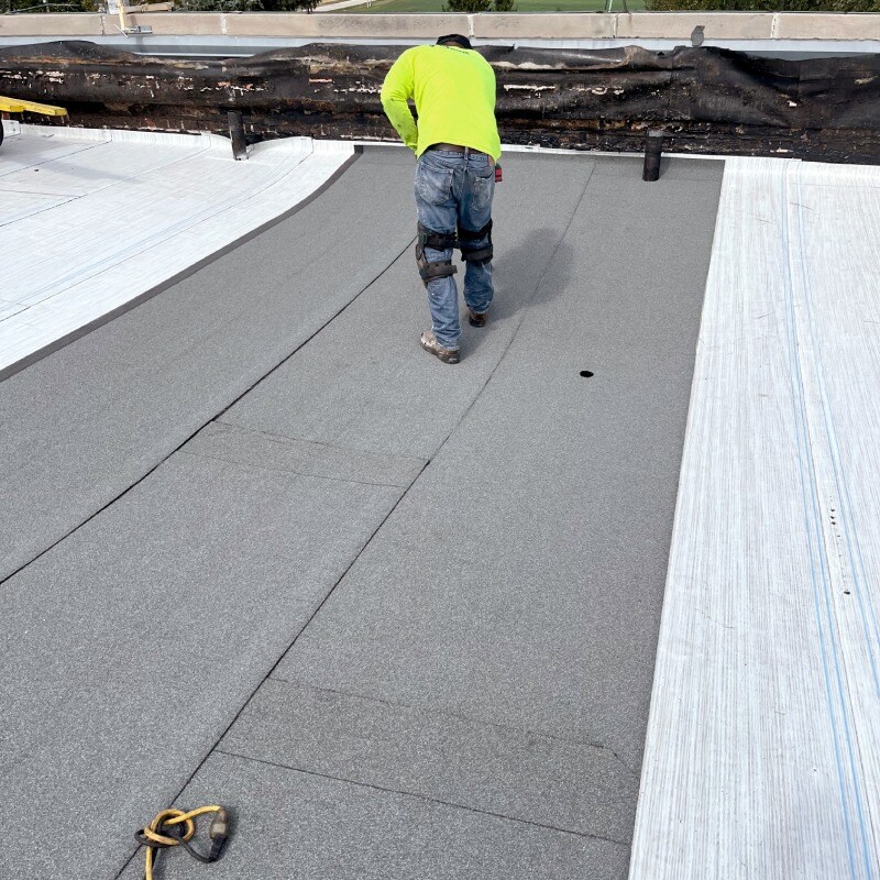 Contractor installing sbs roofing materials on a commercial roof with curves