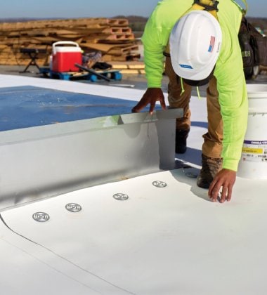 Roofing contractor bending down to install materials