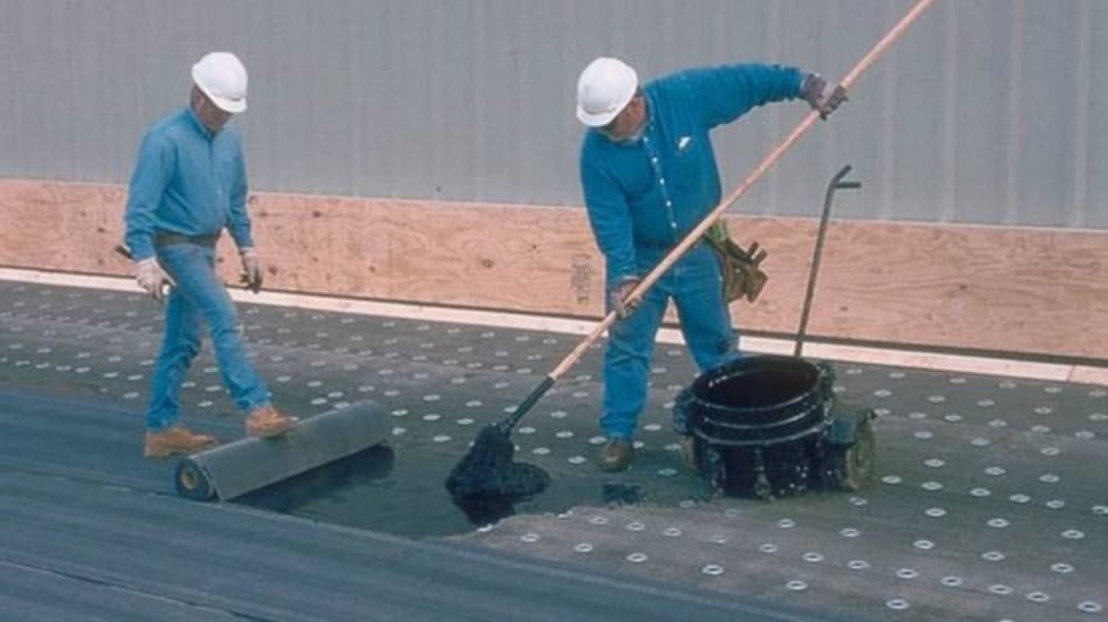 Roofers using hot asphalt method to install SBS roofing materials