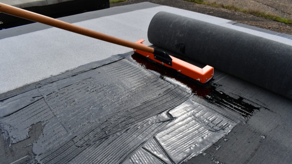 Roofers using cold adhesives to install SBS roofing materials