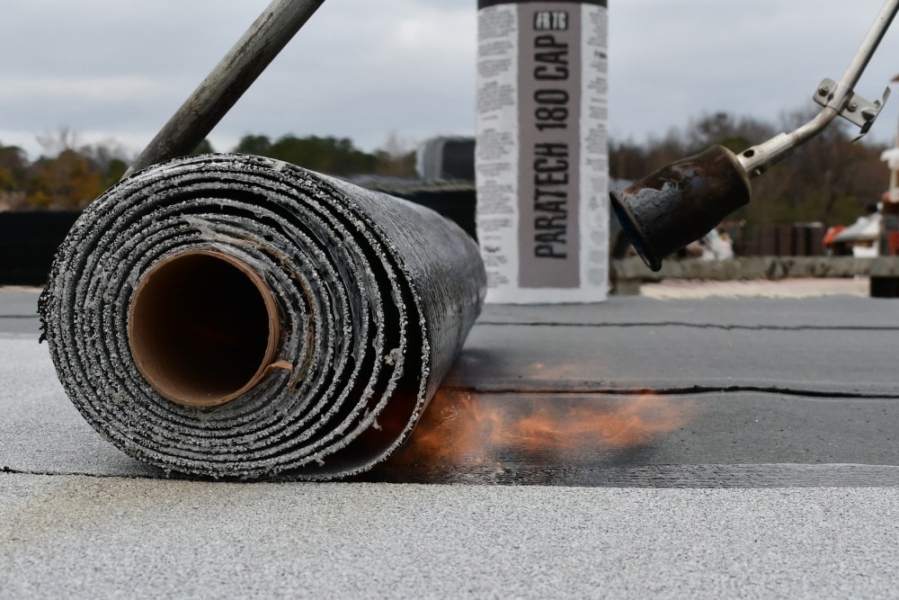 Roofers using torch applied method to install SBS roofing materials